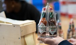 Ein Mitarbeiter der Caritas Werkstatt für Menschen mit Behinderung München hält fertig verpackte Tabasco-Flaschen in der Hand | © Caritas Werkstatt für Menschen mit Behinderung München