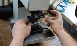 Ein Metallteil wird mithilfe einer Maschine verbogen | © Caritas Werkstatt für Menschen mit Behinderung München