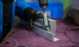 Schrauben werden mit einem Akkuschrauber an einem Metallteil befestigt  | © Caritas Werkstatt für Menschen mit Behinderung München