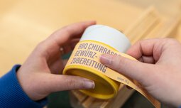 Auf einen Behälter mit Gewürz wird ein Blatt mit Informationen zum Gewürz geklebt | © Caritas Werkstatt für Menschen mit Behinderung München
